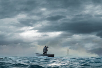 A businessman on a boat looking ahead at a light tower.