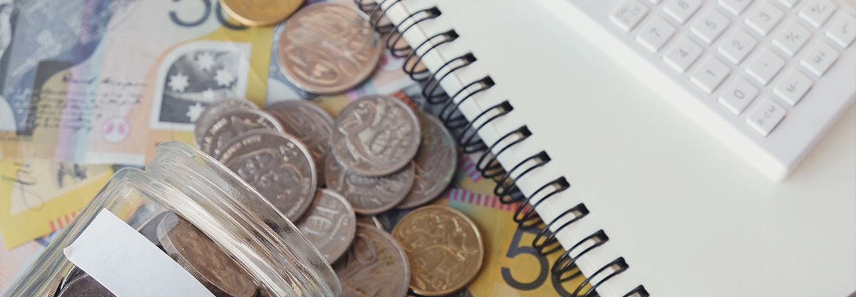 Image of coins and bills with a notebook and a calculator.